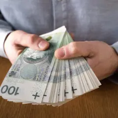 Dłonie trzymające plik banknotów 100 zł. Czy to symbol najlepiej płatnych zawodów?