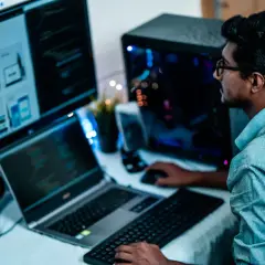 Un homme concentré sur ses écrans, le bon distance ecran yeux pour coder.