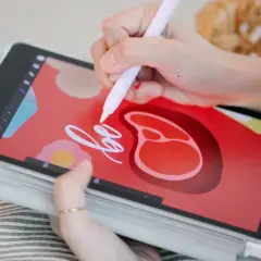 Dłoń rysuje na tablecie graficznym stylizowany stek i napis "be".
