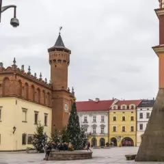 Rynek w Tarnowie zimową porą. W centralnym punkcie placu stoi choinka, a w tle widać zabytkowe kamienice i wieżę ratuszową.