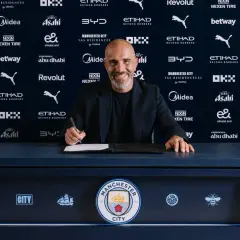 Uśmiechnięty trener Manchesteru City podpisuje kontrakt.