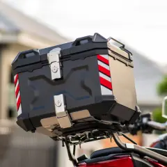 Czarny, solidny bagażnik na kufer motocyklowy z odblaskowymi pasami. Gotowy na dalekie podróże.