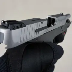 Dłoń w czarnej rękawicy trzyma pistolet. To nie jest najdroższy pistolet na świecie, ale jego precyzja i jakość wykonania budzą podziw.