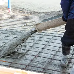 Betoniarz wylewa beton na zbrojenie, które zawiera włókna polipropylenowe, tworząc solidną posadzkę.