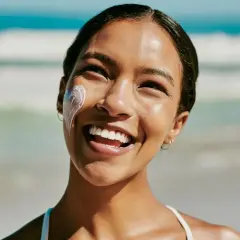 Strahlendes Lächeln am Strand, Sonnencreme schützt vor Hautalterung.