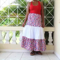 A woman models a long, tiered skirt with a colorful, mosaic-like pattern. The skirt features a white middle tier, creating a flowing, bohemian look.