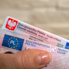 Dłoń trzyma polski dowód osobisty i prawo jazdy. To ważne dokumenty, a prawo jazdy bezterminowe daje swobodę na drogach.