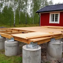 Byggnation av altan på betongplintar. Träkonstruktionen är på plats och förbereds för trall.