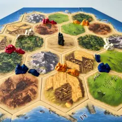 Plansza do gry osadnicy z Catanu, z pionkami i polami zasobów. Catan instrukcja w tle.