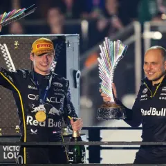 Max Verstappen celebra con un trofeo y champán, junto a Gianpiero Lambiase, tras una victoria.