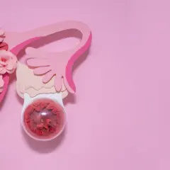 Różowa grafika przedstawia narządy rodne z kwiatami. W okrągłym pojemniku, symbolizującym co to torbiel, widać czerwone płatki.