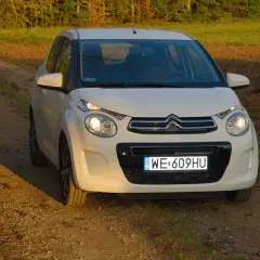 Biały Citroen C1 na tle jesiennego krajobrazu, na drodze gruntowej.