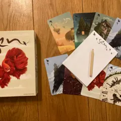 Pudełko gry karcianej "Sen" i rozłożone karty z surrealistycznymi ilustracjami, jak latające wyspy i mroczne zamki.