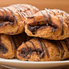 Cuatro napolitanas de chocolate apiladas en un plato blanco, con un glaseado de chocolate oscuro.