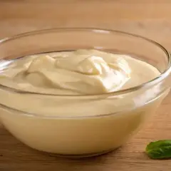 Kremowy sos czosnkowy jak z restauracji w szklanej miseczce, z listkiem bazylii obok.