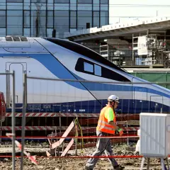 Budowa stacji, pracownik w kamizelce odblaskowej przechodzi obok pociągu Pendolino. Ile jedzie pociąg z Krakowa do Kołobrzegu?