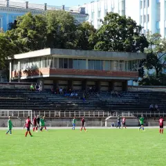 Młodzi piłkarze trenują na boisku. W tle widać trybuny i budynek, część stadionu Dynamo Kijów.