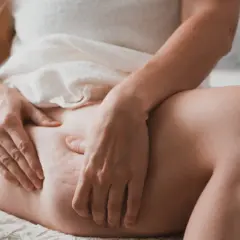 Kobieta bada swoje uda, szukając sposobów, jak pozbyć się cellulitu. Widoczne nierówności skóry sugerują problem.