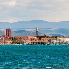 Widok na miasto Koper w Słowenii z turkusowym morzem w tle. W oddali widać góry.