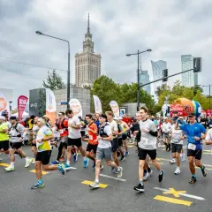 Uczestnicy biegną w maratonie, pokonując jego długość. W tle Pałac Kultury i Nauki.