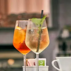 Dwa orzeźwiające drinki, jeden pomarańczowy z plasterkiem cytryny, drugi jasny z miętą i słomką. Idealne na letnie popołudnie.