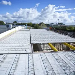 Budowa nowego stropu nad halą przemysłową. Metalowe kratownice i zbrojenie czekają na beton.