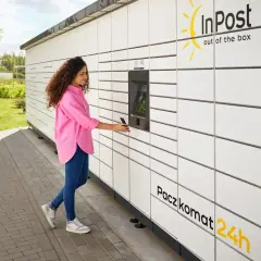 Kobieta z telefonem przy Paczkomacie InPost. Gdzie jest kurier InPost? Pewnie zaraz tu będzie, by odebrać paczkę.
