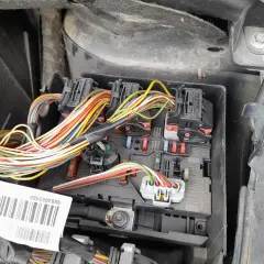Widok na skrzynkę z bezpiecznikami i wiązką przewodów w Peugeot 307. Widać kolorowe kable i oznaczenia bezpieczników.