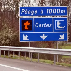Panneau "Péage à 1000m" avec logo orange "t" et icône de carte. Indique dans quel sens mettre le badge télépéage Vinci.