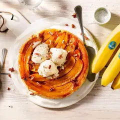 Eine köstliche gebackene Banane Tarte mit Vanilleeis und Pekannüssen, daneben frische Chiquita Bananen.