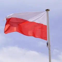 Biało-czerwona flaga powiewa na maszcie. Duma i symbole narodowe Polski w błękitnym niebie.