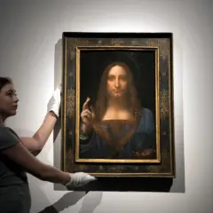 Kobieta w białych rękawiczkach prezentuje obraz "Zbawiciel świata". Ciekawe fakty o tym dziele Leonarda da Vinci.