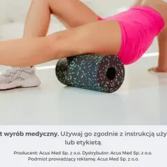 Kobieta wykonuje rolowanie mięśni ud na czarnym wałku z zielonymi kropkami, dbając o regenerację.