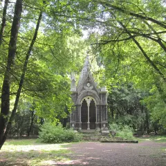 Un piccolo tempietto gotico nel **bosco delle fate a Torre Alfina**, circondato da alberi rigogliosi e sentieri ombrosi.