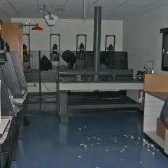Wnętrze ciemni fotograficznej z kilkoma powiększalnikami, stołem laboratoryjnym i zlewem.