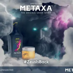 Metaxa 12 cena. Zeus powraca! Butelka Metaxy Zeus Edition i szklanka z bursztynowym trunkiem na tle burzy i twarzy Zeusa.