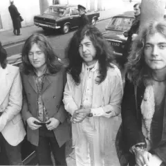 Czterech członków Led Zeppelin pozuje do zdjęcia na ulicy. John Bonham, John Paul Jones, Jimmy Page i Robert Plant wyglądają stylowo.