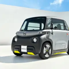 Najmniejszy Opel, Rocks-e, z żółtymi akcentami, prezentuje się nowocześnie na tle białej ściany i błękitnego nieba.
