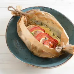 Bar au barbecue en papillote, garni de rondelles de tomates et de citron, prêt à être dégusté.
