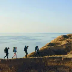 Fyra vandrare med ryggsäckar går längs en klippkant vid havet. En fantastisk vandring i Europa.