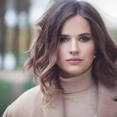 Mujer con peinados media melena modernos, ondas suaves y un abrigo beige.