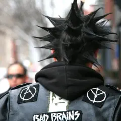 Un ragazzo con cresta punk e giacca di pelle con toppe, un'icona dei gruppi punk anni 2000.