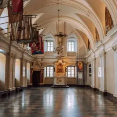 Wnętrze klasztoru na Jasnej Górze, gdzie można podziwiać liczne częstochowa atrakcje, w tym ołtarz i wiszące sztandary.