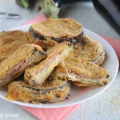 Cordon bleu di melanzane impanati e fritti, ripieni di prosciutto e formaggio filante, serviti su un piatto bianco.