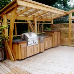 En vacker murad grillplats med inbyggd grill och förvaring under ett träskydd. Perfekt för sommarens middagar utomhus.