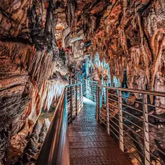 Sentiero illuminato tra stalattiti e stalagmiti nelle grotte in Toscana. Un viaggio sotterraneo tra formazioni rocciose millenarie.