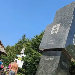 Trójstyk granic Bieszczady: monumentalny obelisk z herbami Słowacji i Ukrainy, otoczony zielenią.