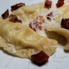 Pierogi, en klassisk polsk mat, serveras med riven ost och tärnat fläsk.