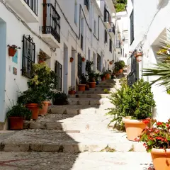 Calle empedrada con escaleras y casas blancas adornadas con macetas. Un ejemplo de los pueblos bonitos cerca de Vera.
