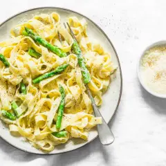 Pyszny makaron ze szparagami w sosie śmietanowym, posypany parmezanem. Idealny na lekki obiad.